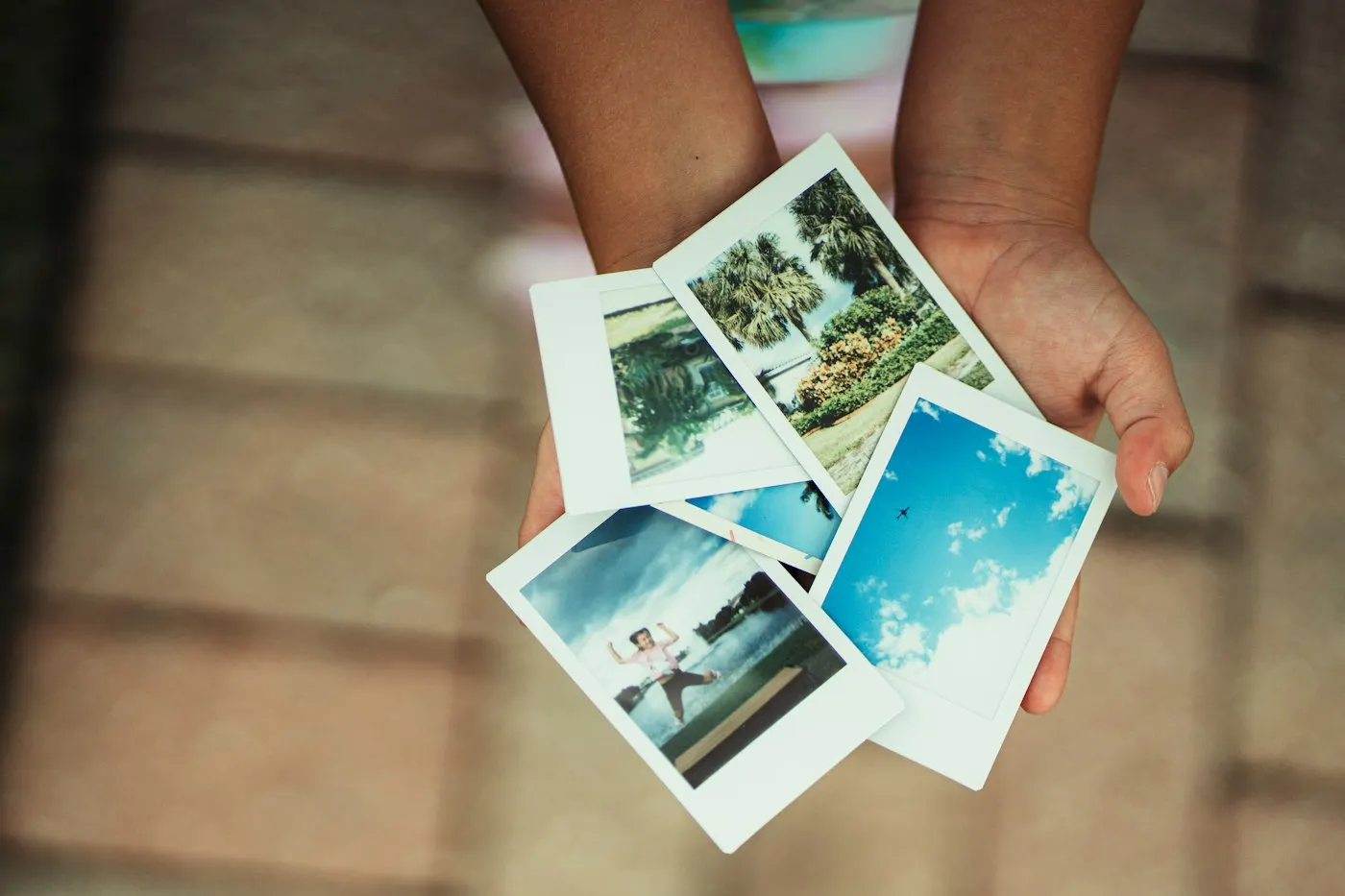 Manos sosteniendo varias fotos impresas
